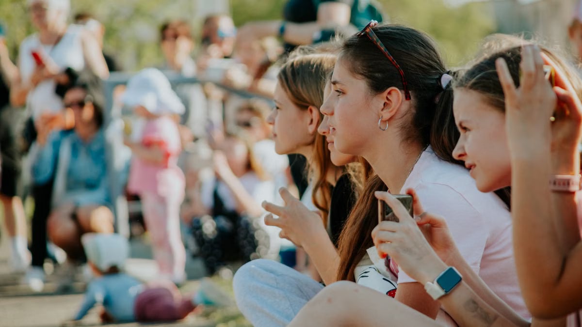 Group of teenagers enjoying an outdoor summer event filled with people and activities.